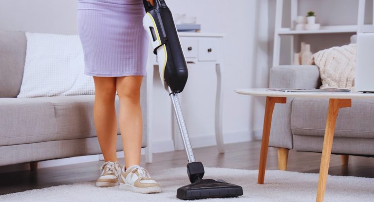 Aspirateur balai sans fil utilisé sur un tapis de salon