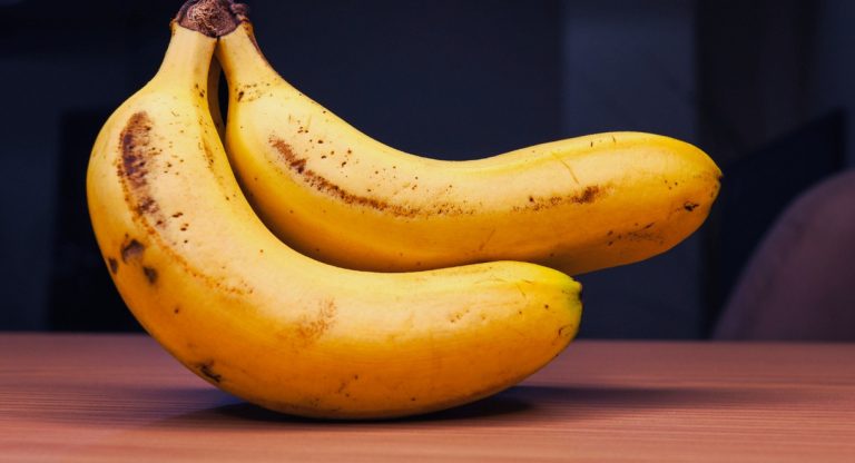 bananes jaunes bien mûres tachetées posées sur une table en bois