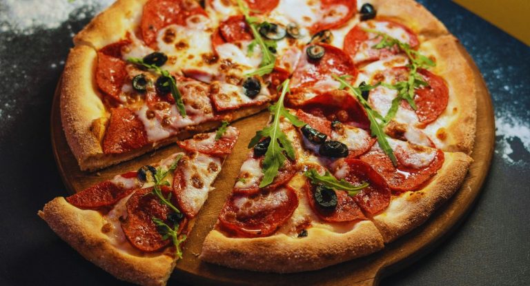 Pizza au pepperoni et olives sur planche en bois
